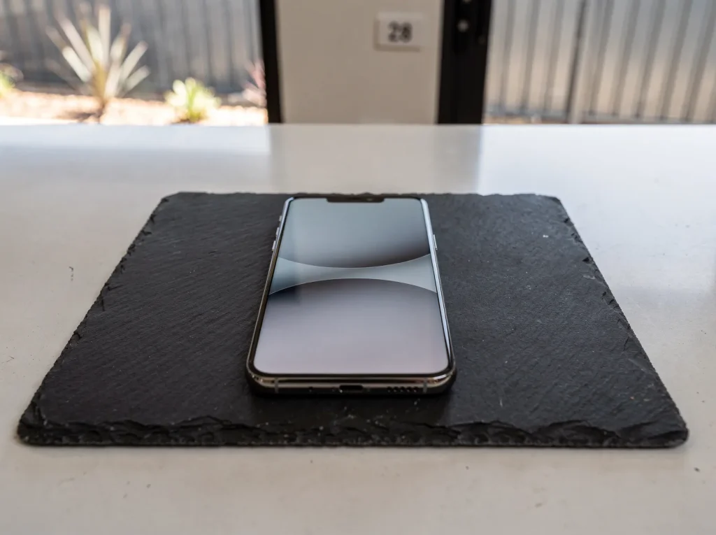 Flagship smartphone with freshly repaired OLED display flat on a West Perth repair workbench.